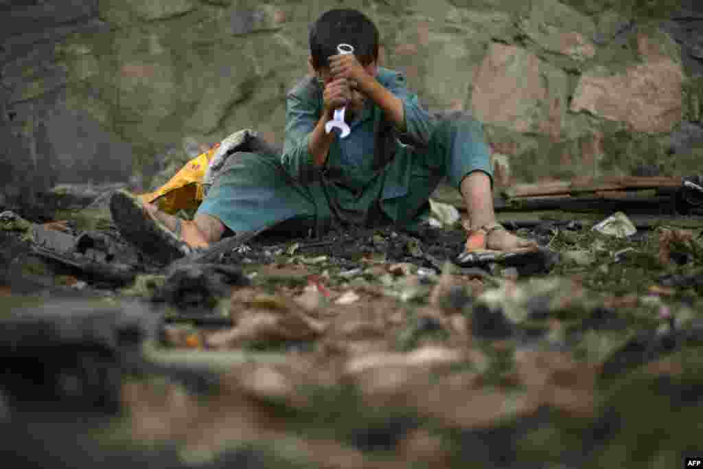 A child uses a wrench as he searches for scrap metal in Kabul, Afghanistan, July 26, 2022.