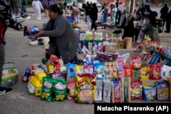 A vendor completes a transaction at a market where people can buy or barter goods, near Buenos Aires, Argentina, Aug. 10, 2022. (AP Photo/Natacha Pisarenko)