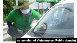 Một nhân viên dán thẻ trả phí đường bộ không dừng lên một xe ô tô ở Việt Nam. 