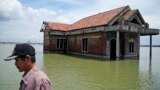 FILE - A man walks past a house abandoned after it was inundated by water due to the rising sea level in Sidogemah, Central Java, Indonesia, Nov. 8, 2021. Climate hazards such as flooding, heat waves and drought have worsened known infectious diseases in people. (AP Photo)