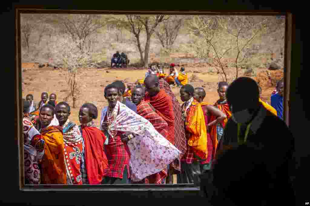 Maasai waiting in line to cast their votes, look through an open window at electoral officials inside a polling station at Niserian Primary School, in Kajiado County, Kenya.