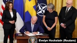 Predsednik SAD Džo Bajden potpisuje Protokol o pristupanju Švedske i Finske NATO-u, u društvu potpredsednice Kamale Haris, švedske ambasadorke Karin Olofsdoter i finskog ambasadora Mika Hautale, 9. avgust 2002. 