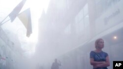 The flag of Ukraine hangs over people walking through a haze of cooling mist at a shopping center in Dnipro, Ukraine, Aug. 17, 2022. 