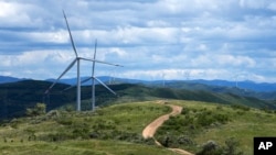 Tourists ride horses near Wind turbines on the grassland in Zhangbei county, in north China's Hebei province on Aug. 15, 2022. 