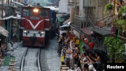 Khách du lịch chụp ảnh đoàn tàu hướng về Ga Hà Nội trên đoạn đường sắt xuyên qua nội đô. Một báo cáo dự án đường sắt cao tốc Bắc-Nam, từng bị Quốc hội từ chối cách đây hơn 10 năm, sẽ được trình lên Bộ Chính trị xem xét vào tháng 9.