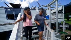 FILE - Louise Billiot, left, a member of the United Houma Nation Indian tribe, walks around the home of her friend and tribal member Irene Verdin , in Pointe-aux-Chenes, La., on May 26, 2022. Hurricane Ida heavily damaged Verdin's home.