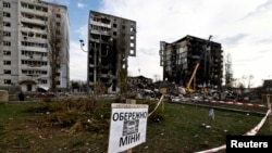 Предупреждающий знак с надписью «Осторожно, мины» на фоне зданий, которые были разрушены российскими военными в результате обстрелов в Бородянке, Киевская область, 7 апреля 2022 года