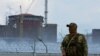 Российский военный на фоне захваченной Запорожской АЭС, 8 августа 2022 года
