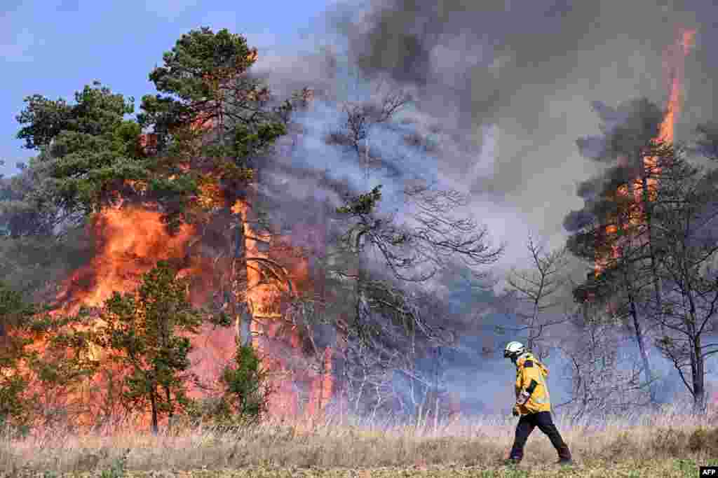 A firefighter walks in front of trees in flame during a wildfire in Boyne, southern France, in the &quot;Grands Causses natural park.&quot;