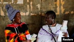 Maasai traditional women talk near a voting booth at a polling center before casting their ballots during the general election at a primary school in Kajiado county, Kenya, Aug. 9, 2022.
