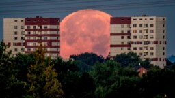 The full moon sets behind apartment houses in the outskirts of Frankfurt, Germany. 