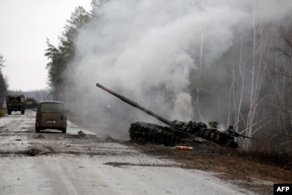 Smoke rises from a Russian tank destroyed by Ukrainian forces on the side of a road in the Luhansk region, Feb. 26, 2022.  