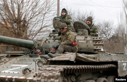 Service members of pro-Russian troops in uniforms without insignia sit atop a tank in the separatist-controlled settlement of Buhas, in Donetsk, Ukraine, March 1, 2022.  