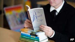 Amanda Darrow, director of youth, family and education programs at the Utah Pride Center, poses with books, including "The Bluest Eye," by Toni Morrison. (AP Photo/Rick Bowmer, File)