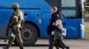 Жители Мариуполя, покинувшие убежище на металлургическом комбинате «Азовсталь», идут к автобусу в сопровождении военнослужащего российской армии (AP)