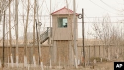FILE - A security person watches from a guard tower around a detention facility in Yarkent County in northwestern China's Xinjiang Uyghur Autonomous Region on March 21, 2021.