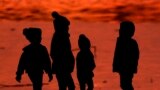 FILE - Children are silhouetted against a pond at a park in Lenexa, Kan., on Saturday, Dec. 26, 2020. Health officials remain perplexed by mysterious cases of severe liver damage in hundreds of young children around the world. (AP Photo/Charlie Riedel, File)