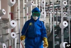 An employee of Songyo Knitwear Factory in Songyo district disinfects the work floor in Pyongyang, North Korea, May 18, 2022, after Kim Jong Un said Tuesday his party would treat the country's outbreak under the state emergency. (AP Photo/Jon Chol Jin)