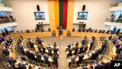 Литовские законодатели стоя приветствуют Владимира Зеленского перед тем, как выслушать его видеообращение. 12 апреля 2022 г. 