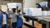 Des travailleurs déchargent des boîtes d'environ 500 000 doses données de vaccin chinois Sinopharm lors d'une cérémonie dans la capitale économique Bujumbura le 14 octobre 2021. (Photo AFP/ CHANDROU NITANGA)