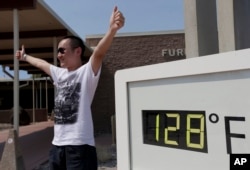 Cheng Jia, of China, poses by a digital thermometer at the Furnace Creek Vistitor Center in Death Vally National Park