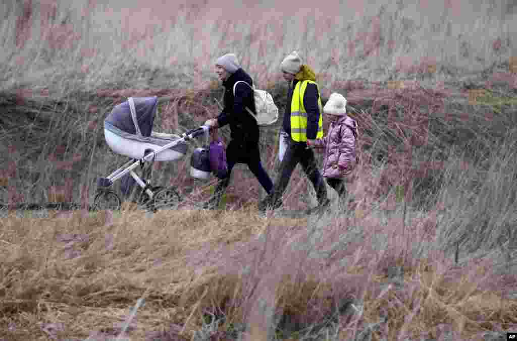 Una mujer con su bebé camina con otras personas que huyen de Ucrania, en el cruce fronterizo de Medyka, Polonia.