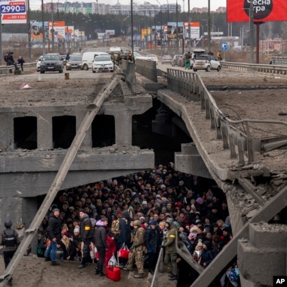 A crowd of Ukrainians are visible under the destroyed cross-section of a bridge on the outskirts of Kyiv, Ukraine.