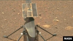 The Ingenuity Mars helicopter’s carbon fiber blades can be seen in this image, taken from video that was captured by the Mastcam-Z instrument aboard NASA’s Perseverance Mars rover on April 8, 2021. (Image Credit: NASA/JPL-Caltech/ASU)