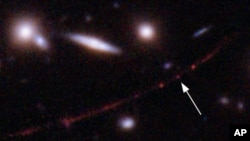 This image made available by NASA on Wednesday, March 30, 2022, shows the star Earendel, indicated by arrow, and the Sunrise Arc galaxy, stretching from lower left to upper right. 