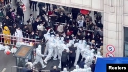 FILE - Residents confront workers donned in protective suits who are blocking the entrance of a residential compound, amid the coronavirus disease (COVID-19) outbreak in Shanghai, China, in this still image obtained from a social media video released November 30, 2022. (Video obtained by Reuters/via REUTERS)