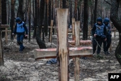 Украинские саперы ищут противопехотные мины на месте захоронения погибших на окраине Изюма, города на востоке Украины (архивное фото)