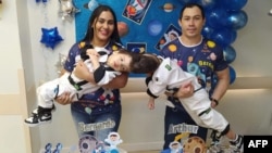Handout photo taken on an unspecified date of conjoined twins Bernardo (L) and Arthur (R) with their parents Adriely (L) and Antonio Lima (R). (AFP PHOTO/Handout/Arthur Pereira/Fitamarela)