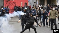 Un hombre lanza un cilindro de gas lacrimógeno durante choques entre la policía y cocaleros en La Paz, Bolivia, el 8 de agosto de 2022. Foto AFP.