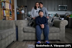 Eleonor Obedoza, her husband Arman, and son Angelo, 12, sit inside their new three-bedroom apartment in Daly City, California, July 8, 2022. (AP Photo/Godofredo A. Vásquez)
