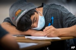 Angel Cardenas, a freshman at Hiram Johnson High School, wears his mask as he works on a math worksheet, Monday, June 6, 2022. (Hector Amezcua/The Sacramento Bee via AP, File)