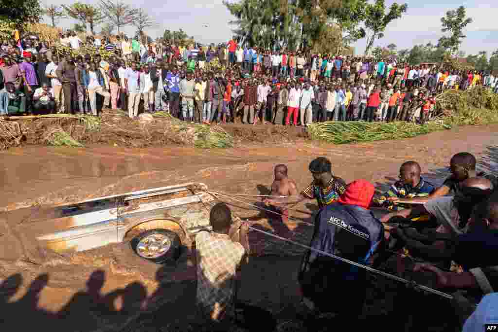 Villagers try to pull up the minibus in which 14 bodies were found inside in the River Nabuyonga in Namakwekwe, eastern Uganda, August 1, 2022.&nbsp;Two rivers burst their banks on the weekend after the city was battered by heavy rainfall.