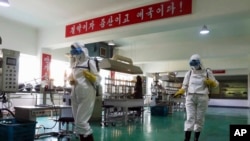 북한 평양 시내 공장 내부를 지난 6월 방역 요원들이 소독하고 있다. (자료사진)