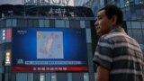 北京市民在观看街头电子屏幕上官媒央视播放的中国军队在台湾附近举行实弹军演的报道。（2022年8月4日）