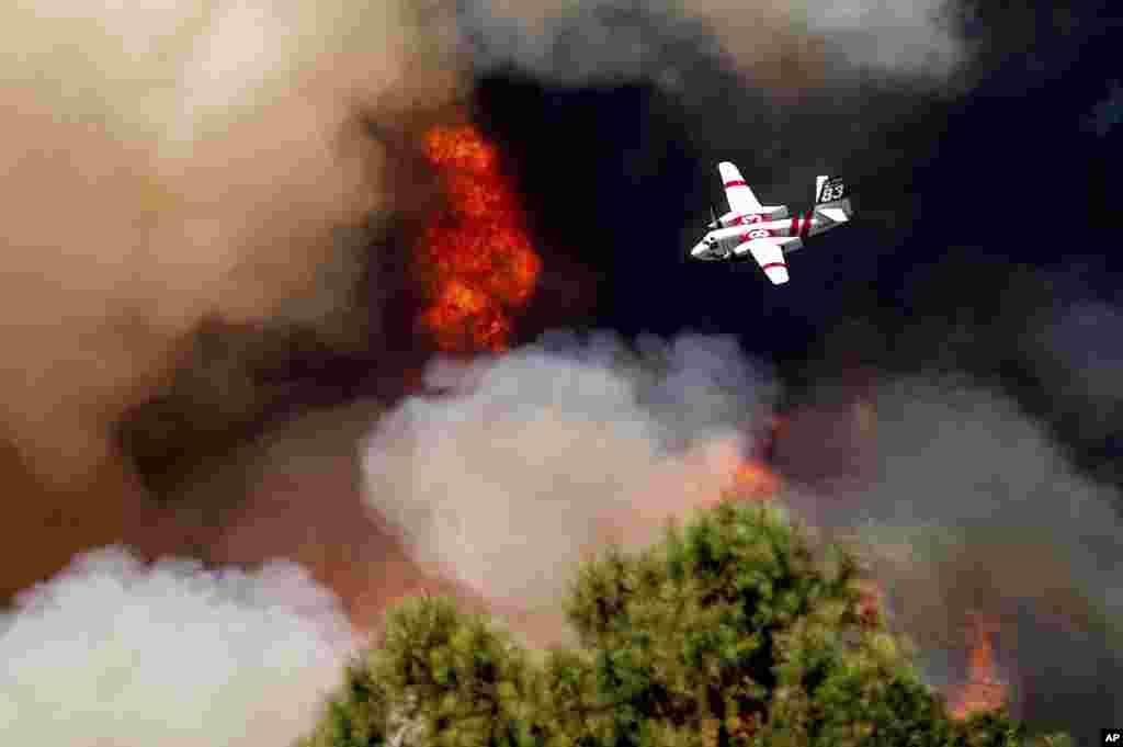 An air tanker flies past flames while battling the Oak Fire in Mariposa County, California, July 24, 2022.