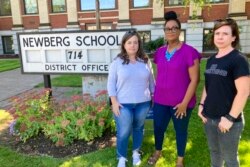 From left, Beth Woolsey, Tai Haden-Moore and AJ Schwanz , who are members of a group called Newberg Equity in Education advocating for inclusion and equity in schools, stand in front of a school district office in Newberg, Ore., on Sept. 21, 2021.