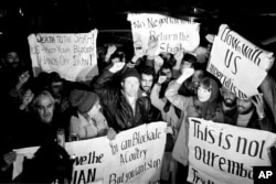 FILE - Americans who support Iran's position in the hostage crisis join with Iranians in anti-American demonstrations outside the U.S. Embassy in Tehran , Dec. 15, 1979. (AP Photo/Mohammad Sayad)