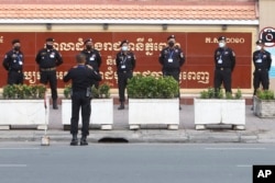 FILE - Cambodian police officers have a short meeting before a hearing for Rong Chhun, president of the Cambodian Confederation of Unions, in front of the Phnom Penh Municipal Court on Aug. 18, 2021
