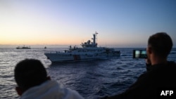 FILE - Personel Penjaga Pantai Filipina merekam kapal Penjaga Pantai China selama misi pasokan di Laut Cina Selatan yang disengketakan, 5 Maret 2024. (JAM STA ROSA / AFP)