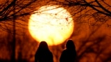 FILE - People watch the sunset at a park on an unseasonably warm day, Feb. 25, 2024, in Kansas City, Mo. (AP Photo/Charlie Riedel, File)
