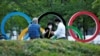 People chat next to Olympic Rings monument outside the Japan Olympic Committee (JOC) headquarters near the National Stadium, the main stadium for the 2020 Tokyo Olympic Games that have been postponed to 2021, in Tokyo, June 23, 2021.