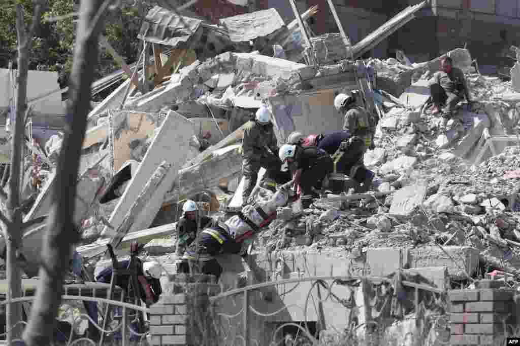 Rescuers remove the body of a person from a destroyed building that was hit by a missile strike in the Ukrainian town of Sergiyvka, near Odessa, killing at least 18 people and injuring 30.