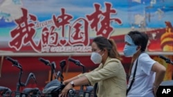 騎著電動車的中國女子駛過中國夢的宣傳畫。（2022年6月20日）
