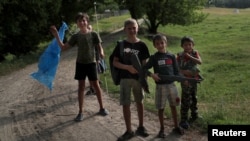  Дети играют неподалеку от места проведения учений территориальных сил самообороны Украины на окраине Харькова, 17 июня 2022 года