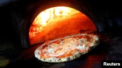 FILE - Pizza Margherita is prepared in a wood-fired oven at L'Antica Pizzeria da Michele in Naples, Italy December 6, 2017. (REUTERS/Ciro De Luca/File Photo)