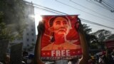 (FILES) In this file photo taken on February 15, 2021, a protester holds up a poster featuring Aung San Suu Kyi during a demonstration against the military coup in front of the Central Bank of Myanmar in Yangon